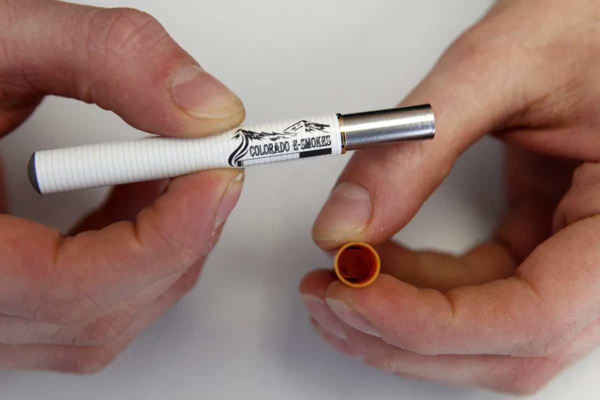 A clerk holds an e-cigarette and the filter end that holds the liquid nicotine solution at a store in Aurora, Colo. (AP Photo/Ed Andrieski)