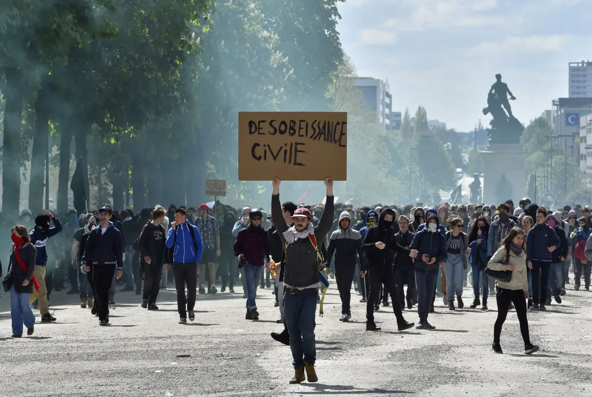 A young man holds a placard reading "Civil Disobedience" as demonstrators take part in a protest against the French government's proposed labor reforms, in Nantes, western France, on April 28, 2016. Protests turned violent in Paris and other French cities today as tens of thousands of workers and students made a new push for the withdrawal of a hotly contested labor bill. (Loic Venance/AFP/Getty Images)