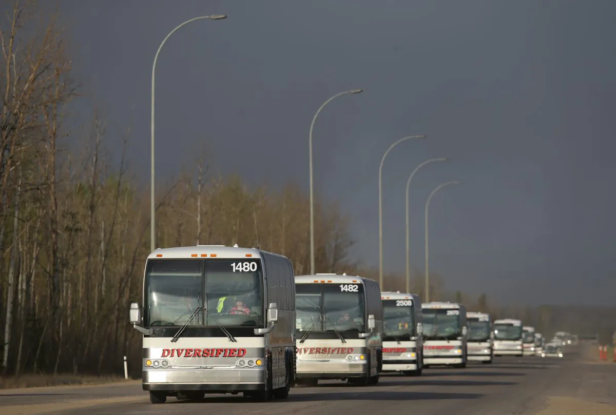 A line of busses make their way through a road block on Highway 63 near Fort McMurray, Alberta, on May 6, 2016. (Cole Burston/AFP/Getty Images)