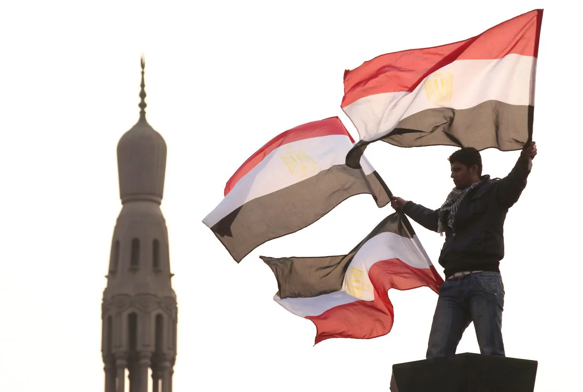 A youth waves Egyptian flags from a lamp post in Tahrir Square in Cairo, Egypt, on Feb. 1, 2011. (Peter Macdiarmid/Getty Images)