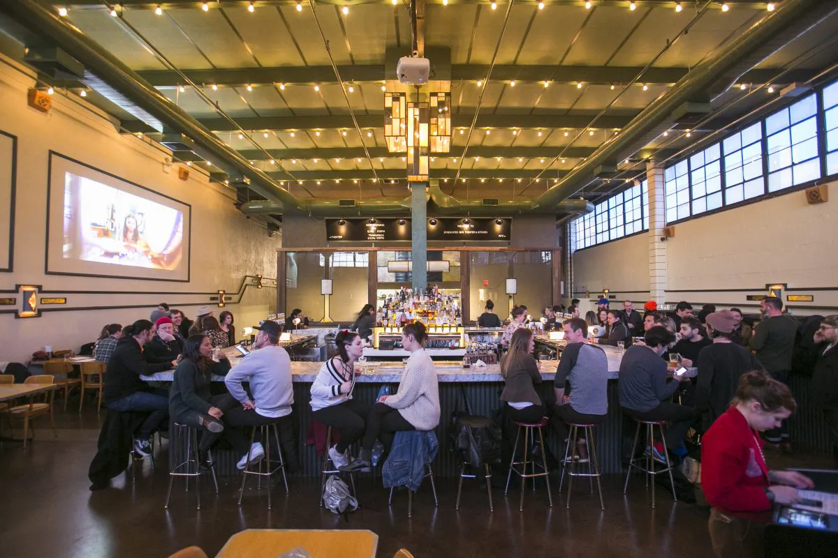 Patrons gather around the bar at Syndicated, a restaurant and movie theater in Bushwick, Brooklyn—many likely waiting for a showing. The theater is in the back, at the end of the corridor on the left. (Samira Bouaou/Epoch Times)