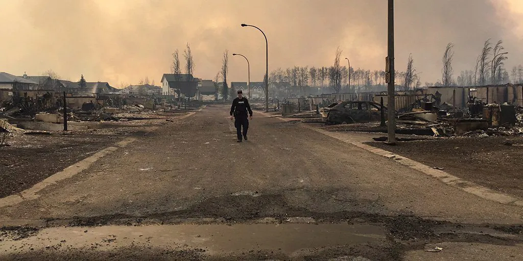 In this May 5, 2016 photo provided by the Royal Canadian Mounted Police Alberta, an RCMP officer surveys the damage on a street in fire-ravaged Fort McMurray, Alberta. (Royal Canadian Mounted Police Alberta via The Canadian Press via AP)