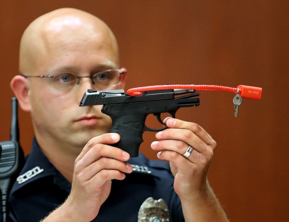 In this June 28, 2013, file photo, Sanford police officer Timothy Smith holds up the gun that was used to kill Trayvon Martin, while testifying in the George Zimmerman trial, in Seminole circuit court in Sanford, Fla. The pistol former neighborhood watch volunteer Zimmerman used in the fatal shooting of Martin is going up for auction online. (AP Photo/Orlando Sentinel, Joe Burbank, Pool, File)
