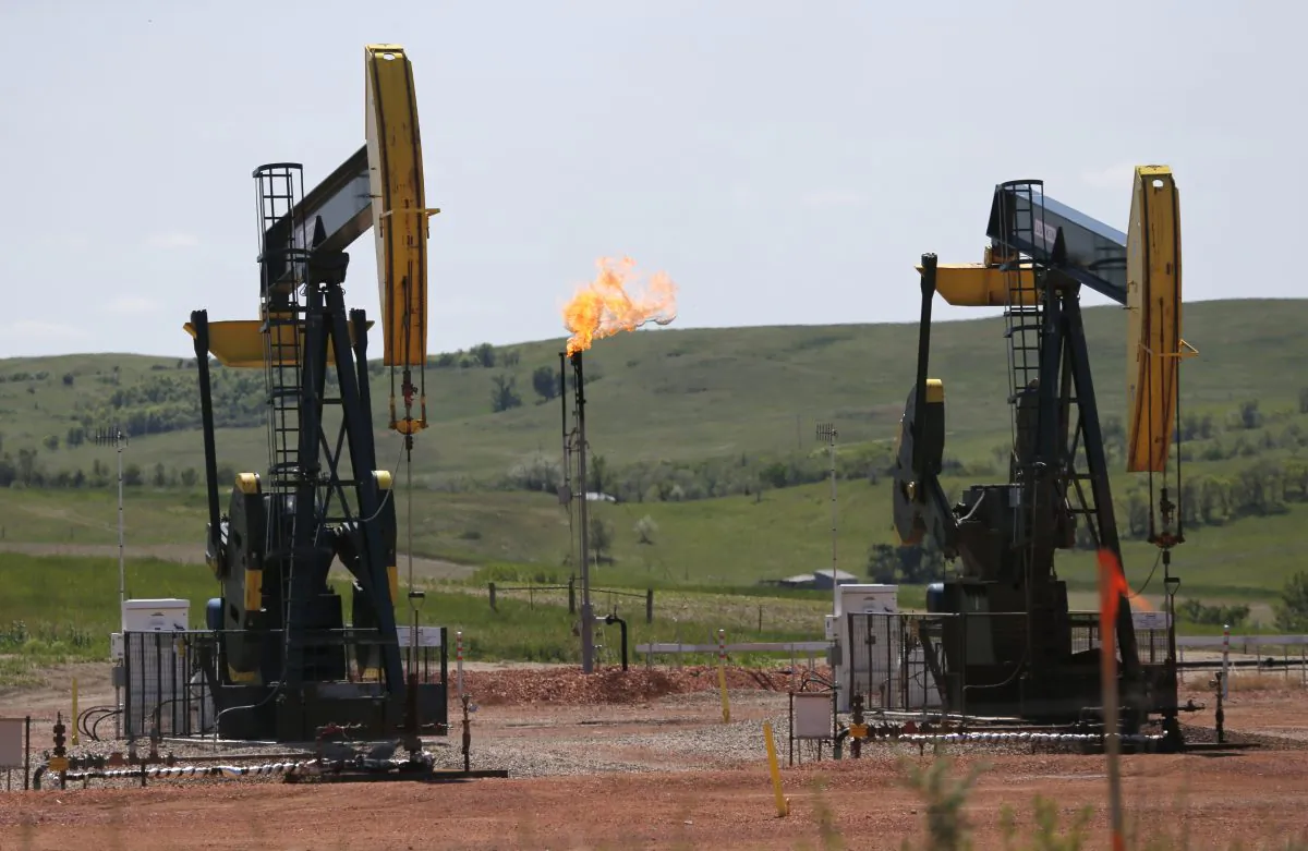 Oil is pumped and natural gas is flared off on an oilfield near Watford City, N.D., on June 12, 2014. (Charles Rex Arbogast/AP Photo)