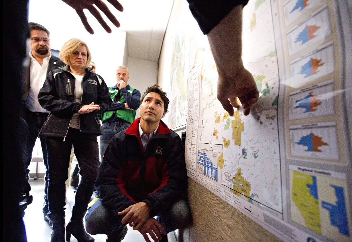 Canadian Prime Minister Justin Trudeau is given a briefing at the Regional Emergency Operation Centre during a visit to Fort McMurray, Alberta, Canada, on May 13, 2016. Alberta officials say 2,432 structures have been destroyed, 530 damaged, and 25,000 saved. The fire is now 930 square miles (2,410 square kilometers) in size and has moved away from the city. It's expected to burn in forested areas for at least a few more weeks. (Jason Franson/The Canadian Press via AP)