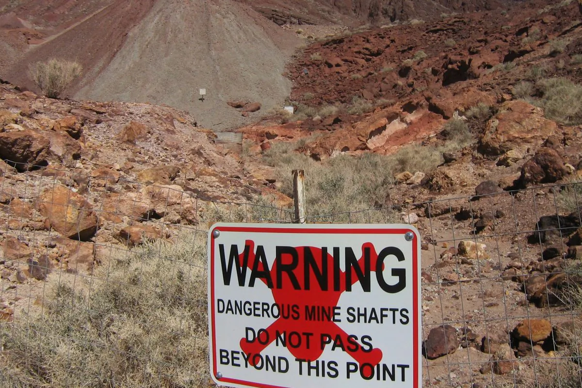 A sign warning people to stay away from a dangerous area of mines and waste-rock piles is pictured in Calico Ghost Town, Calif. (Scottthezombie, CC BY-SA)