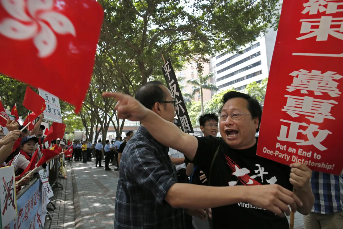 A pro-democracy activist, right, waves banner and shout slogans against pro-government protesters, left, outside the convention center where the Chinese Communist Party's third-highest ranking official, Zhang Dejiang, gave a speech during a visit to Hong Kong, Wednesday, May 18, 2016. Hong Kong authorities rolled out a massive security operation on Tuesday as they braced for protests during a top Beijing official's visit to the semiautonomous city, where tensions are rising over Chinese rule.(AP Photo/Vincent Yu)