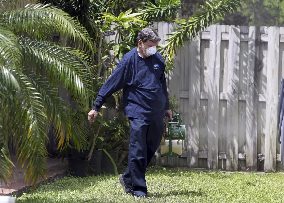 In this photo taken April 12, 2016, Giraldo Carratala, an inspector with the Miami- Dade County, Fla. mosquito control unit, sprays pesticide in the yard of a home in Miami, Fla. (AP Photo/Lynne Sladky)