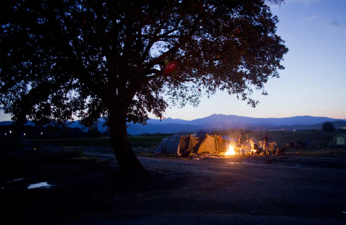 A Group of people sit around a fire camp. (AP Photo/Darko Bandic)