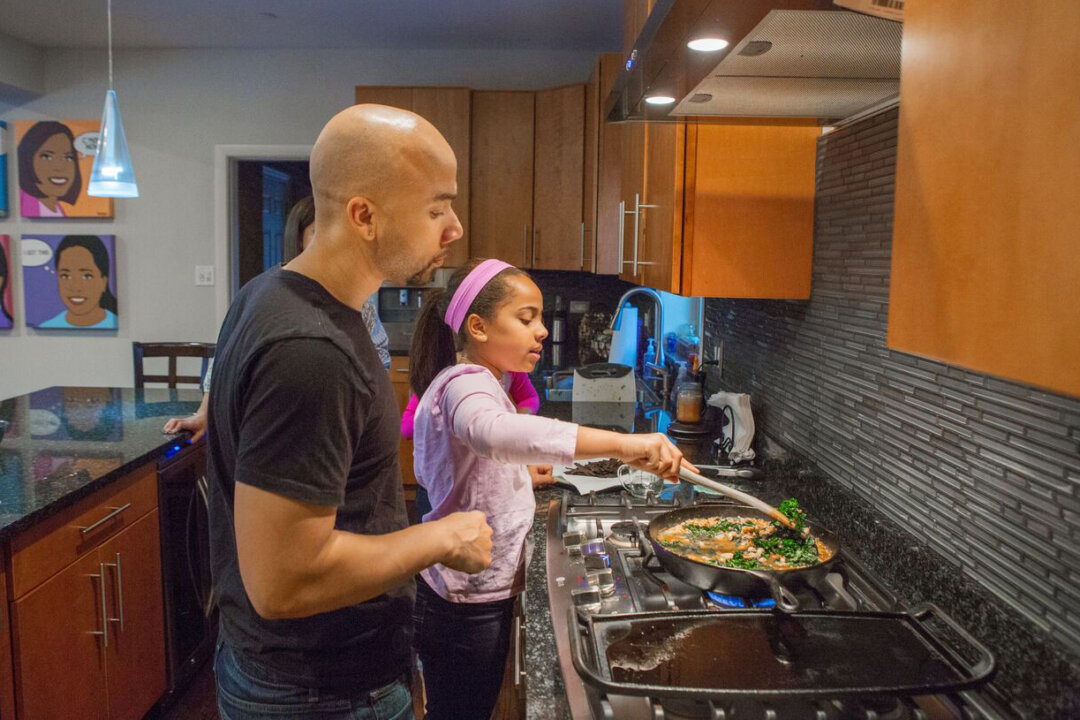 Taryn Robinson cooks white turkey chili, a meal kit dish from Blue Apron, as her father, Keith Robinson, watches over her shoulder in Evanston, Ill., on Jan. 23, 2016. The industry of meal kits is growing quickly and competition is heating up as more players enter the space. (AP Photo/Teresa Crawford)