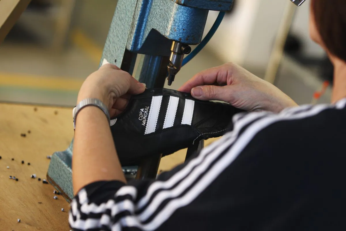 An employee pierces the shoelace holes for a handmade football boot at the factory of German sporting-goods maker Adidas AG on February 23, 2011 in Scheinfeld, Germany. (Alex Grimm/Getty Images)