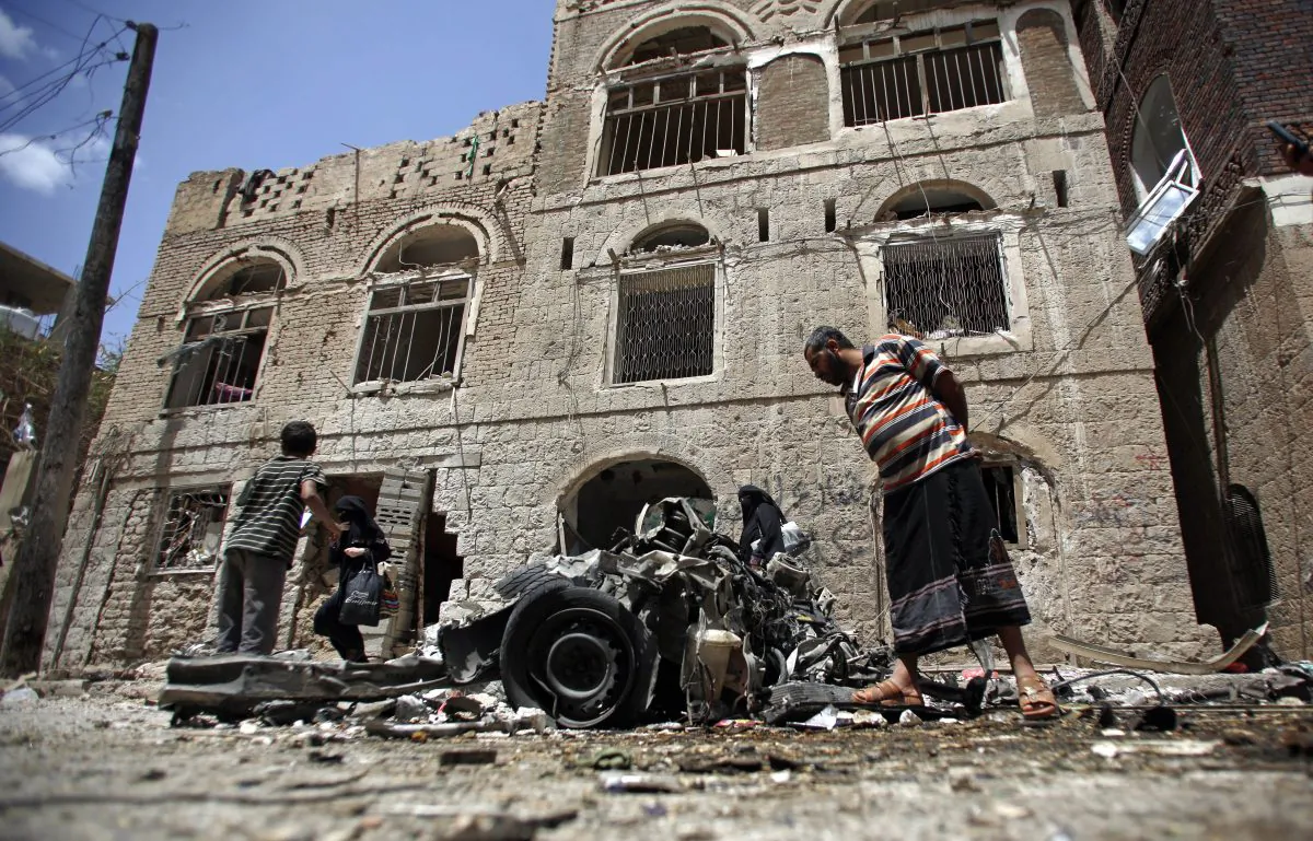 FILE - In this Tuesday, June 30, 2015 file photo, People stand amid wreckage of a vehicle at the site of a car bomb attack near a military hospital in Sanaa, Yemen. The World Health Organization says nearly 1,000 people have been killed worldwide in attacks on medical facilities in conflicts over the past two years in violation of humanitarian norms. (AP Photo/Hani Mohammed)