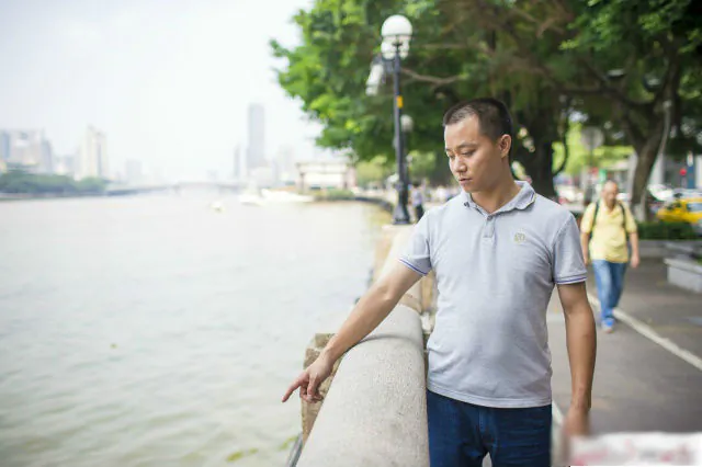 Zhu Liang, a taxi driver, points to the spot where he saved a drowning women at Guangzhou on May 25. (Guangzhou Daily)