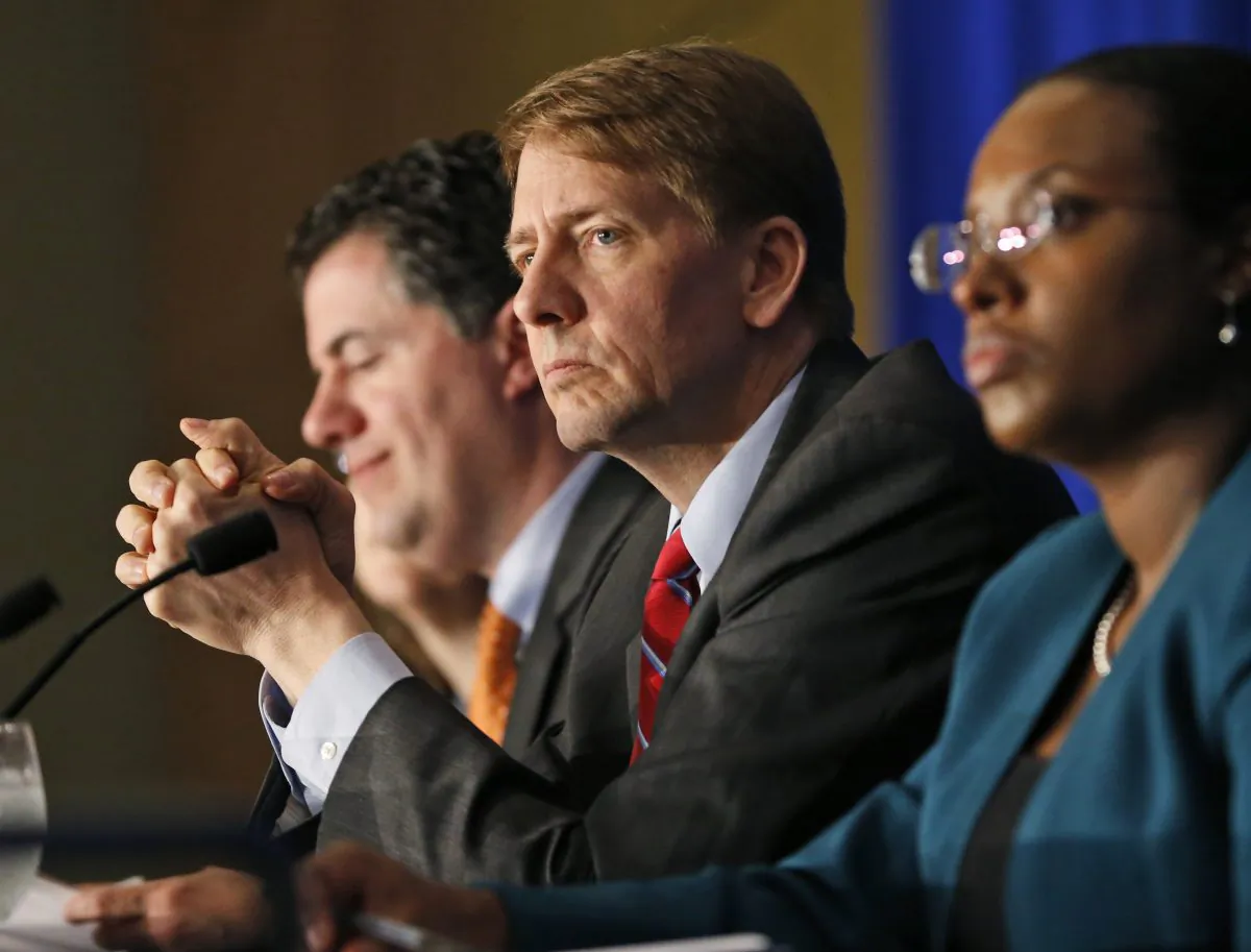 FILE - In this Thursday, March 26, 2015, file photo, Consumer Financial Protection Bureau Director Richard Cordray, center, listens to comments during a panel discussion in Richmond, Va. The CFPB announced Thursday, June 2, 2016, they are proposing a significant clampdown on payday lenders and other providers of high-interest loans, saying borrowers need to be protected from practices that wind up turning into “debt traps” for many. “Too many borrowers seeking a short-term cash fix are saddled with loans they cannot afford and sink into long-term debt,” Cordray said in a prepared statement. (AP Photo/Steve Helber, File)