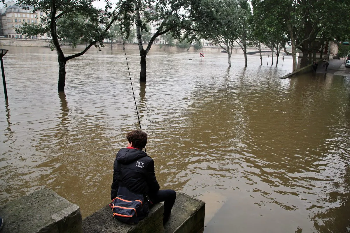 A boy fishes in the Seine river during floods in Paris on June 5, 2016. The riverside Grand Palais exhibition hall in Paris reopened Sunday as floodwaters slowly receded from the French capital, though risks remain for other regions. (AP Photo/Thibault Camus)