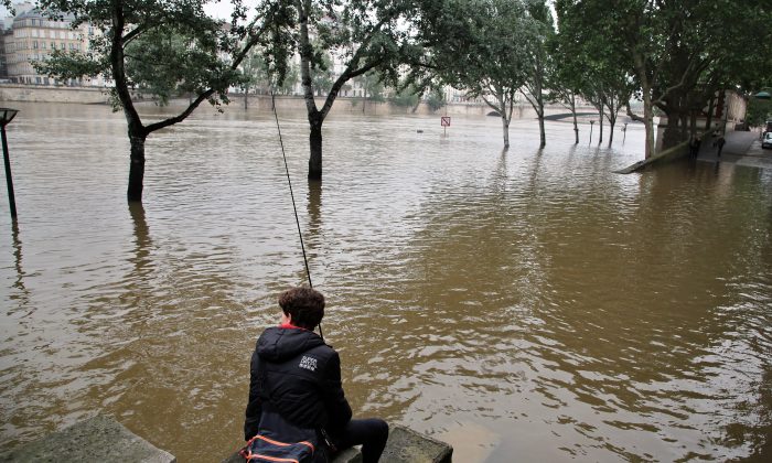 A boy fishes in the Seine river during floods in Paris on June 5, 2016. The riverside Grand Palais exhibition hall in Paris reopened Sunday as floodwaters slowly receded from the French capital, though risks remain for other regions. (AP Photo/Thibault Camus)