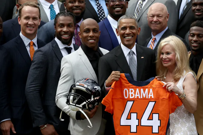 U.S. President Barack Obama holds up a Denver Broncos jersey presented to him as a gift by Annabel Bowlen (R), wife of Broncos majority owner Pat Bowlen, while welcoming the National Football League Super Bowl champion Denver Broncos to the White House Rose Garden on June 6, 2016 in Washington, DC. (Win McNamee/Getty Images)