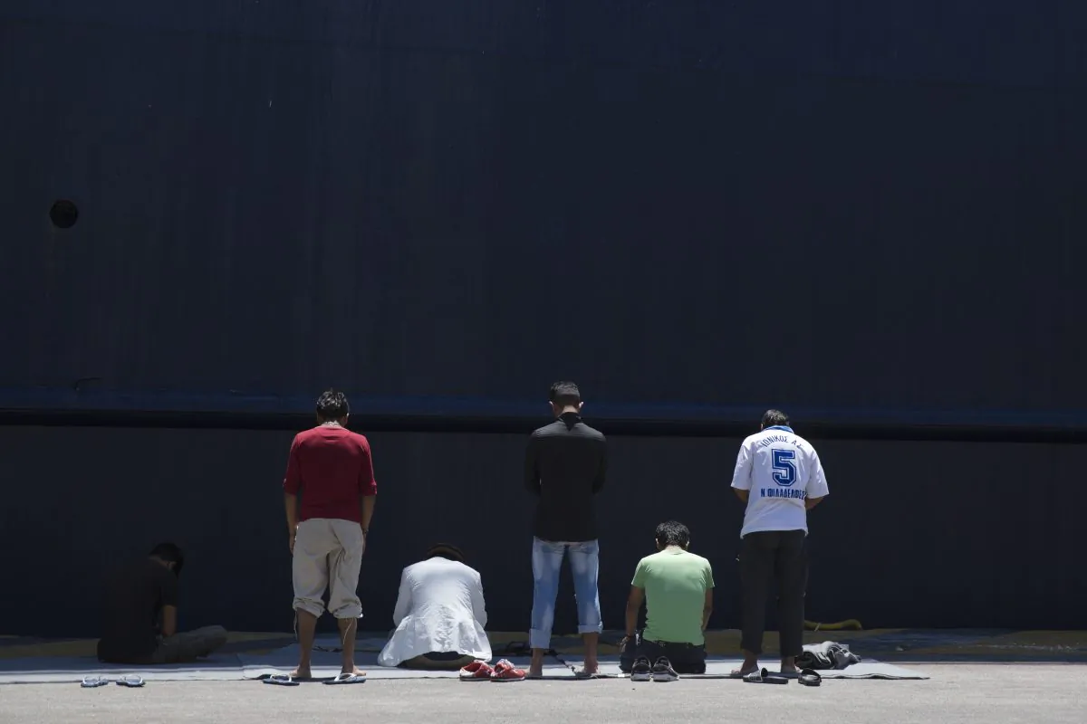 Afghan migrants stranded in Greece pray in front of a docked ferry at the port of Piraeus, near Athens, on the first day of the holy fasting month of Ramadan, on June 6, 2016. (AP Photo/Petros Giannakouris)