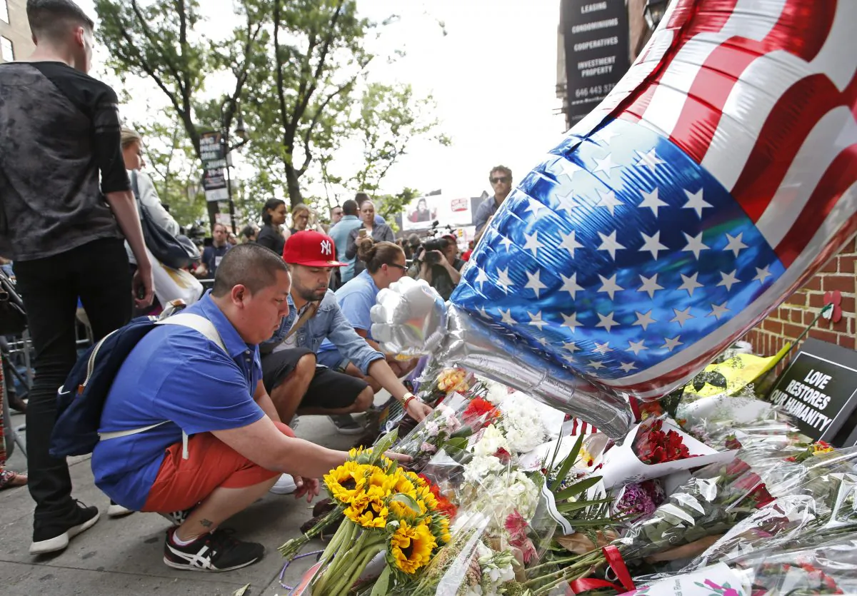Two men lay flowers and mementos during a vigil and memorial for victims of the Orlando nightclub shootings, in New York on June 13. (AP Photo/Kathy Willens)
