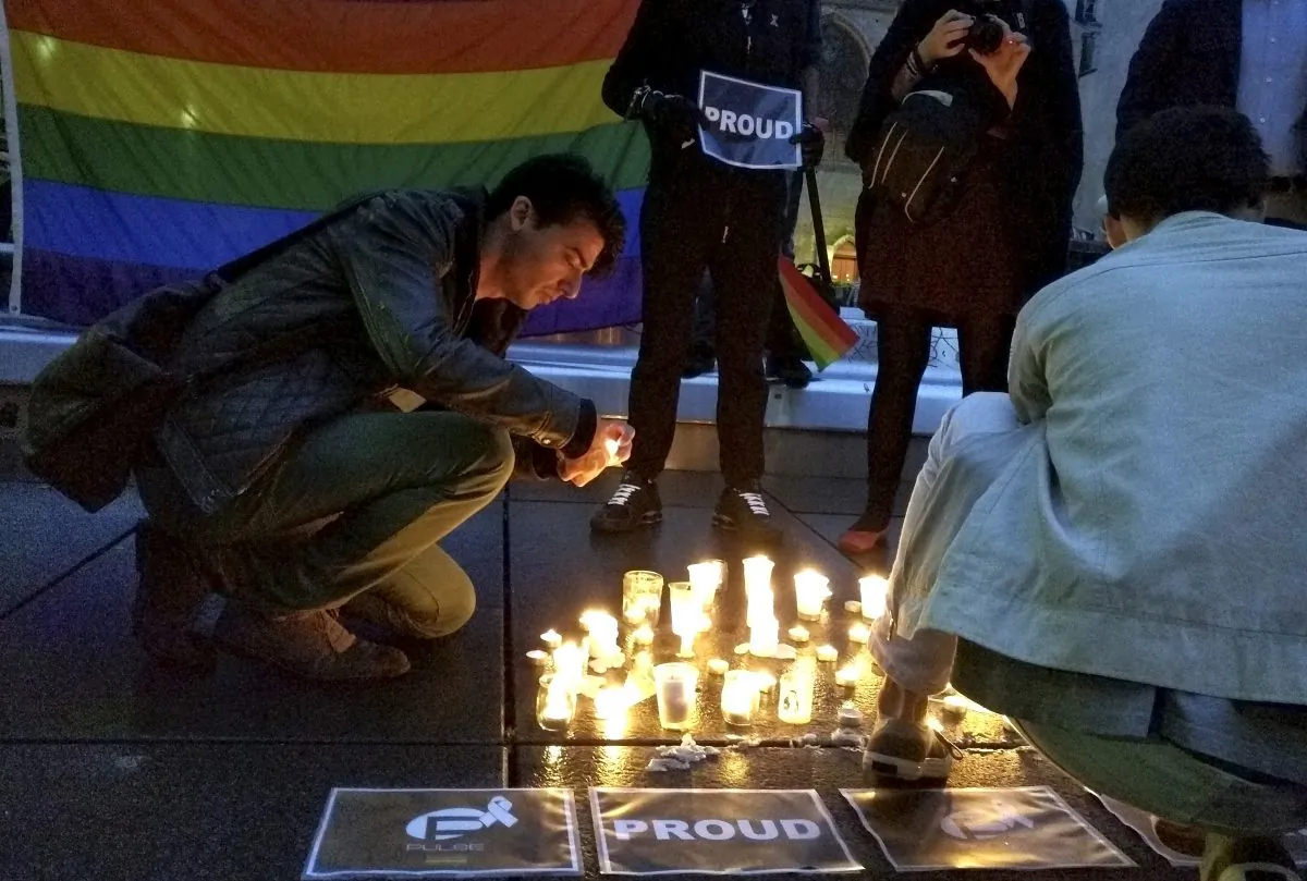 A man lights a candle during a spontaneous  vigil to remember those slain and wounded at an Orlando nightclub, Sunday June 12, 2016 in Paris. (AP Photo/Raphael Satter)