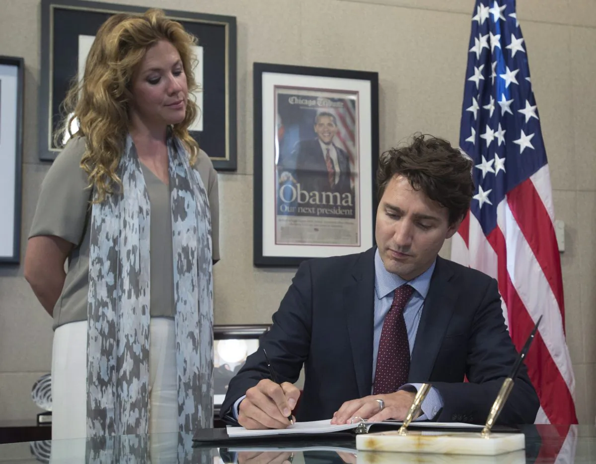 Prime Minister Justin Trudeau signs a book of condolence at the U.S. embassy in Ottawa as Sophie Gregoire Trudeau looks, June 14, 2016. The Prime Minister visited the embassy to pay his respects as Americans grieve the killings of 49 patrons at a gay nightclub in Orlando, Florida. (THE CANADIAN PRESS/Adrian Wyld)