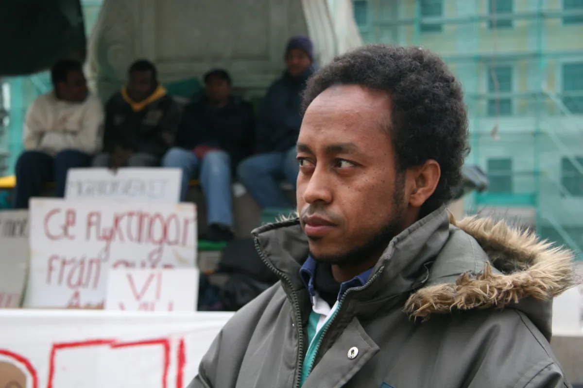 GOTHENBURG, SWEDEN: Omar Dafalla stands to be sent back to war-torn Sudan. Behind him fellow Sundanese refugees hold a sign that reads, in Swedish, "Migration Board: give refugees from Sudan asylum." (Li Dong/The Epoch Times)