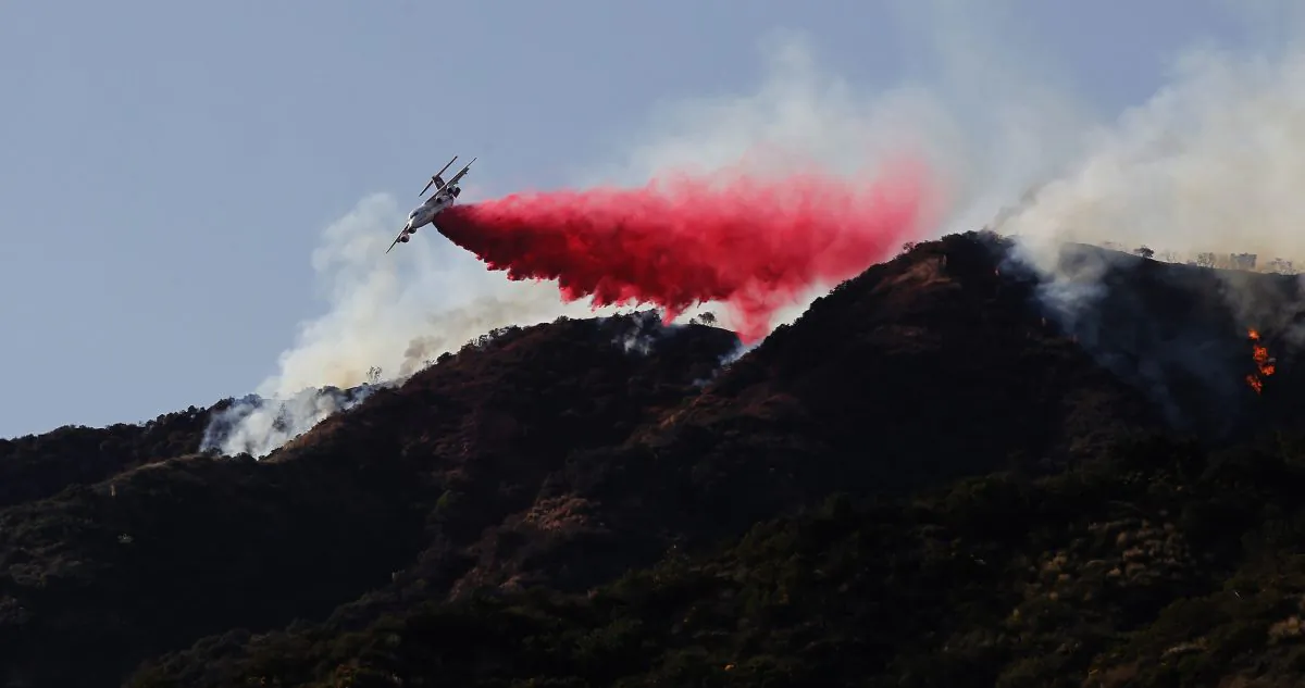 A firefighting plane in a file photo making a retardant drop on a hill near a wildfire in Azusa, Calif., in June 2016. (Nick Ut/AP Photo)