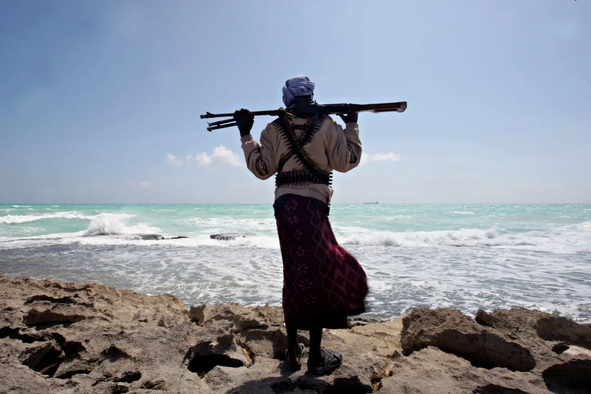 An armed Somali pirate along the coastline while the Greek cargo ship MV Filitsa is seen anchored just off the shores of Hobyo Town in northeastern Somalia where it was then held by pirates, on Jan. 7, 2010. (Mohamed Dahir/AFP/Getty Images)