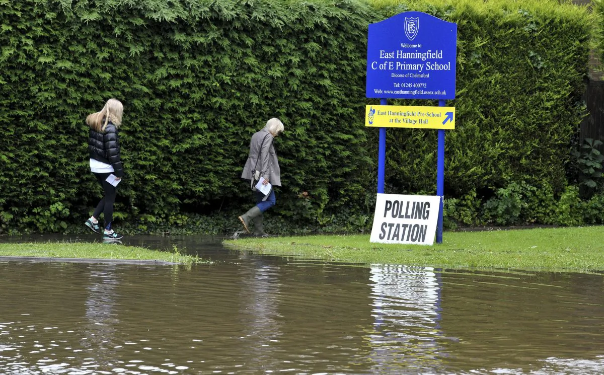 People make their way along a flooded path as they arrive to vote at the polling station in East Hanningfield,  Essex, England, on June 23, 2016. (Nick Ansell/file/PA via AP)