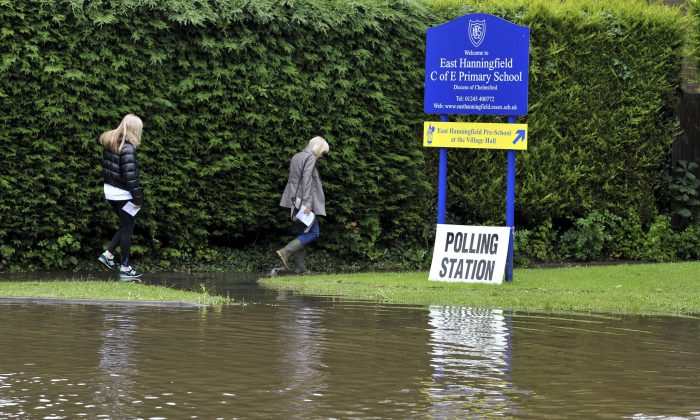 People make their way along a flooded path as they arrive to vote at the polling station in East Hanningfield,  Essex, England, on June 23, 2016. (Nick Ansell/file/PA via AP)