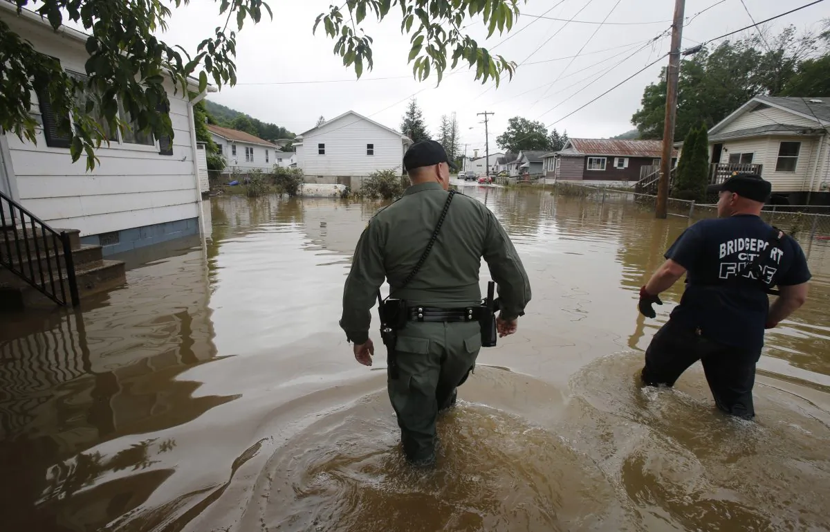 West Virginia State Trooper C.S. Hartman (L) and Bridgeport W.Va. fireman Ryan Moran wade through flooded streets as they search homes in Rainelle, W.Va., on June 25, 2016. Teams were rescuing people from second-story windows, the hoods of cars and the tops of trees as floodwaters drenched southeastern West Virginia. (AP Photo/Steve Helber)
