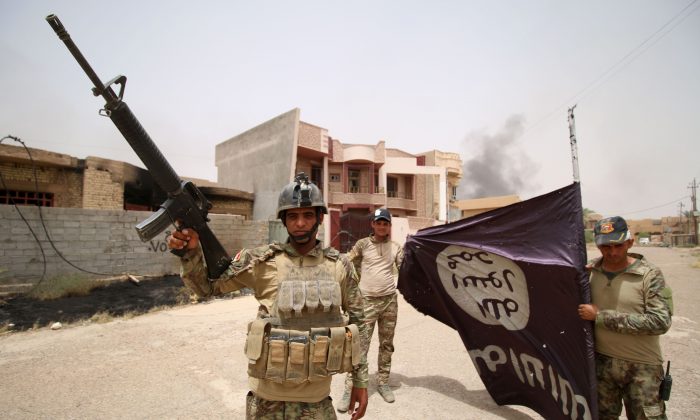 Iraqi pro-government forces hold an ISIS flag in the al-Dhubat II (Officers) neighborhood of Fallujah on June 19, 2016. (Haidar Mohammed Ali/AFP/Getty Images)