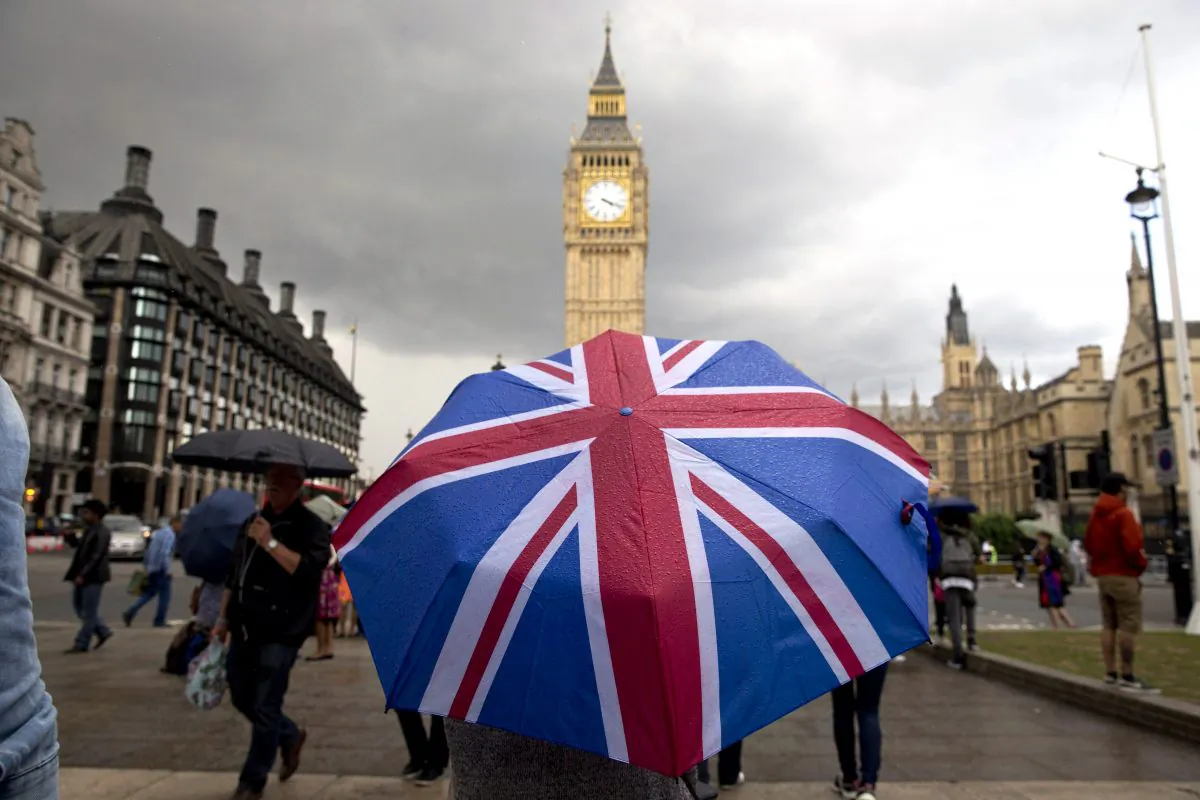 A pedestrian shelters from the rain beneath a Union flag themed umbrella as they walk near the Big Ben clock face and the Elizabeth Tower at the Houses of Parliament in central London on June 25, 2016. (Justin Tallis/AFP/Getty Images)