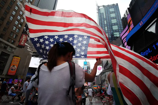 A tourist covers her head with a scarf made like a US flag as she walks under light rain in Times Square on July 4, 2015 in New York. ( JEWEL SAMAD/AFP/Getty Images)