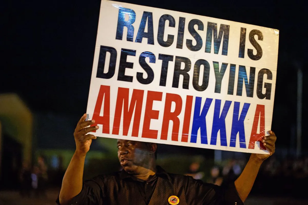 A man holds a sign during a protest on West Florissant Avenue in Ferguson, Missouri, on Aug. 10, 2015. (Michael B. Thomas/AFP/Getty Images)