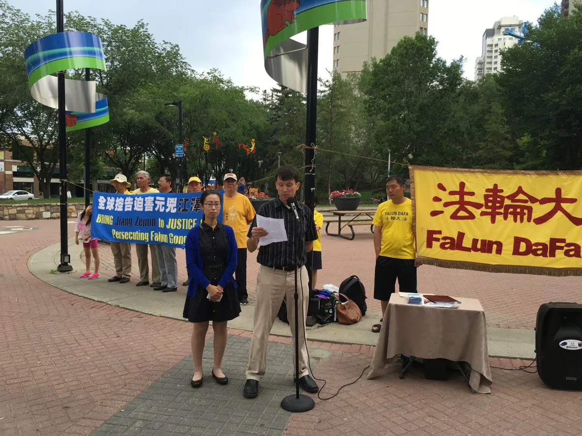 Jay Brauneisen, an Edmonton resident whose mother-in-law, Huixia Chen, has been detained in China for her practice of Falun Dafa, speaks at a rally calling for her release on June 30, 2016 in Edmonton, while his wife Hongyan Lu, Chen’s daughter, looks on. (Omid Ghoreishi/Epoch Times)