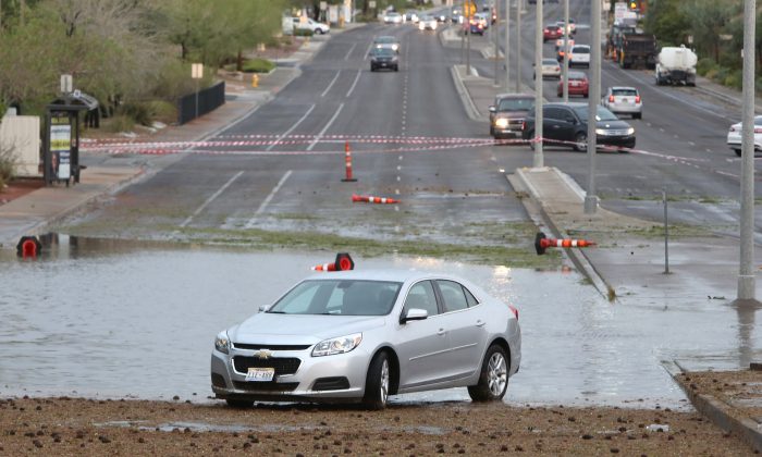 A disabled vehicle sits on Pecos Road near Robindale Road and Windmill Parkway due to flooding as late afternoon storms move through Las Vegas Valley Thursday, June 30, 2016 in Las Vegas. The National Weather Service issued a flash flood warning after intense thunderstorms in mountain and canyon areas near Mount Charleston northwest of Las Vegas. (Bizuayehu Tesfaye/Las Vegas Review-Journal via AP)