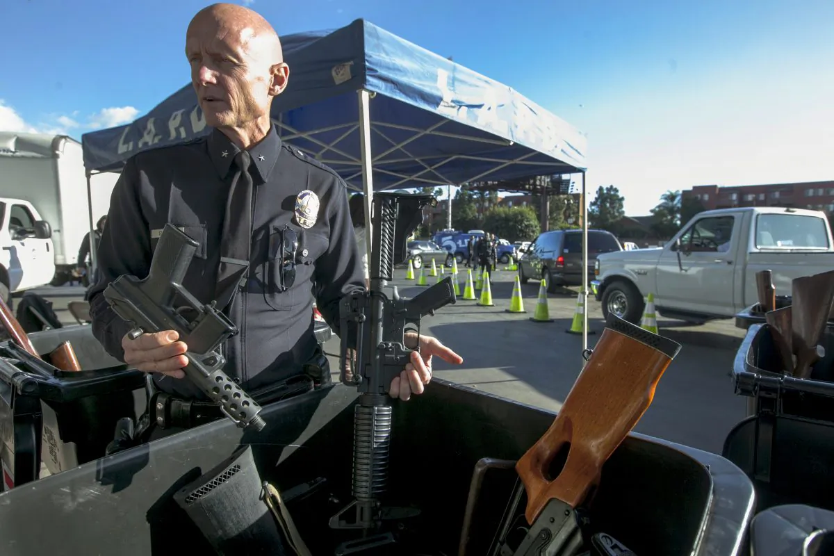 Then Los Angeles Police Cmdr. Andrew Smith, Media Relations and Community Affairs Group, shows assault weapons exchanged at the LA Memorial Sports Arena in Los Angeles on Dec. 26, 2012. (Damian Dovarganes/AP Photo)