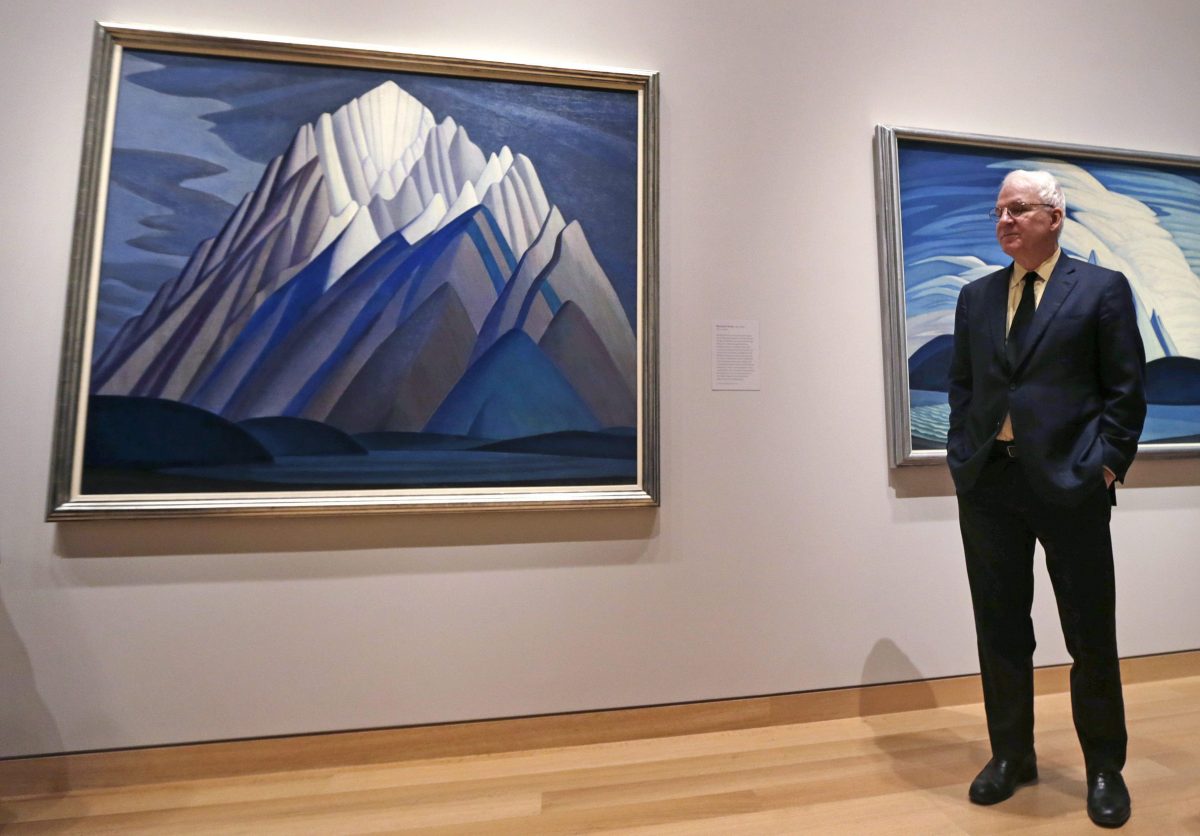 Actor and comedian Steve Martin, who is guest curator of an exhibition at the Museum of Fine Arts devoted to Canadian modernist Lawren Harris, stands next to Harris's "Mountain Forms" painting during a gallery preview at the museum in Boston, Friday, March 11, 2016. "The Idea of North: The Paintings of Lawren Harris" runs through June 12. (AP Photo/Charles Krupa)