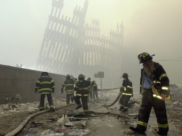 Firefighters work beneath the destroyed mullions, the vertical struts which once faced the soaring outer walls of the World Trade Center towers, after a terrorist attack on the twin towers in New York on Sept. 11, 2001. (AP Photo/Mark Lennihan)
