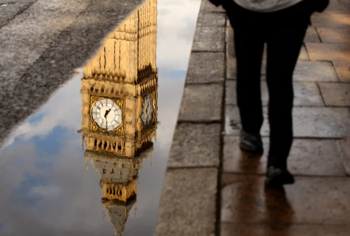 A man walks past a puddle with the reflection of Big Ben's Clock Tower in London, England, on July 14, 2010. (Oli Scarff/Getty Images)