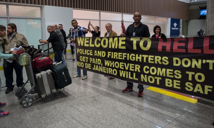 Police officers and firemen welcome passengers with a protest banner at the Tom Jobim International Airport in Rio de Janeiro on July 4. (Vanderlei Almeida/AFP/Getty Images)