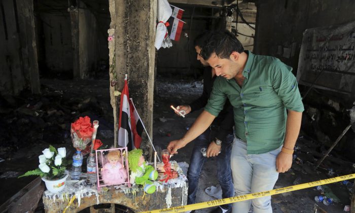 People light candles next to dolls belonging to Rabab Faris, 5, a bomb victim at the scene of Sunday's massive truck bomb attack in the Karada neighborhood, Baghdad, Iraq, Thursday, July 7, 2016. (AP Photo/Karim Kadim)