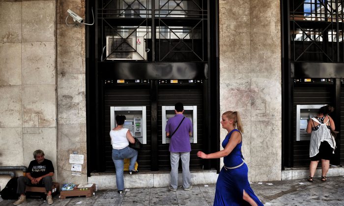 People withdraw money from ATM machines next to a beggar in Thessaloniki on 29th June, 2016. 
For a year the Greeks had to get used to not being able to withdraw more than 420 euros per week from the bank, a measure decided by credit control in full emergency which contributed to the stagnation of the economy.        ( SAKIS MITROLIDIS/AFP/Getty Images)