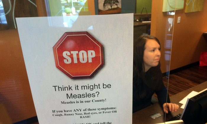 FILE - In this Feb. 7, 2015, file photo, a sign warns of the dangers of measles in the reception area of a pediatrician's office in Scottsdale, Ariz., Saturday, Feb. 7, 2015. Arizona officials are threatening legal action against an immigration detention center south of Phoenix where an outbreak of measles has affected 22 this year, Thursday, July 7, 2016. (AP Photo/Tom Stathis, File)