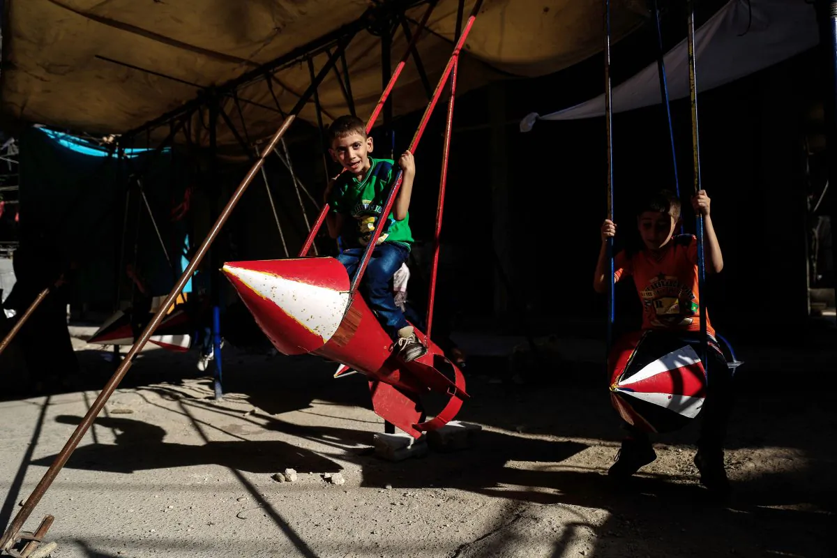 Syrian children play on a swing made out of parts of rockets on July 6, 2016 in the rebel-held town of Douma, 8 miles northeast of the capital Damascus, during the celebrations of Eid al-Fitr holiday, which marks the end of the holy Muslim month of Ramadan. (Sameer al-Doumy/AFP/Getty Images)