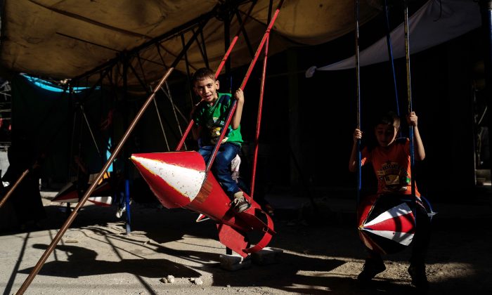 Syrian children play on a swing made out of parts of rockets on July 6, 2016 in the rebel-held town of Douma, 8 miles northeast of the capital Damascus, during the celebrations of Eid al-Fitr holiday, which marks the end of the holy Muslim month of Ramadan. (Sameer al-Doumy/AFP/Getty Images)