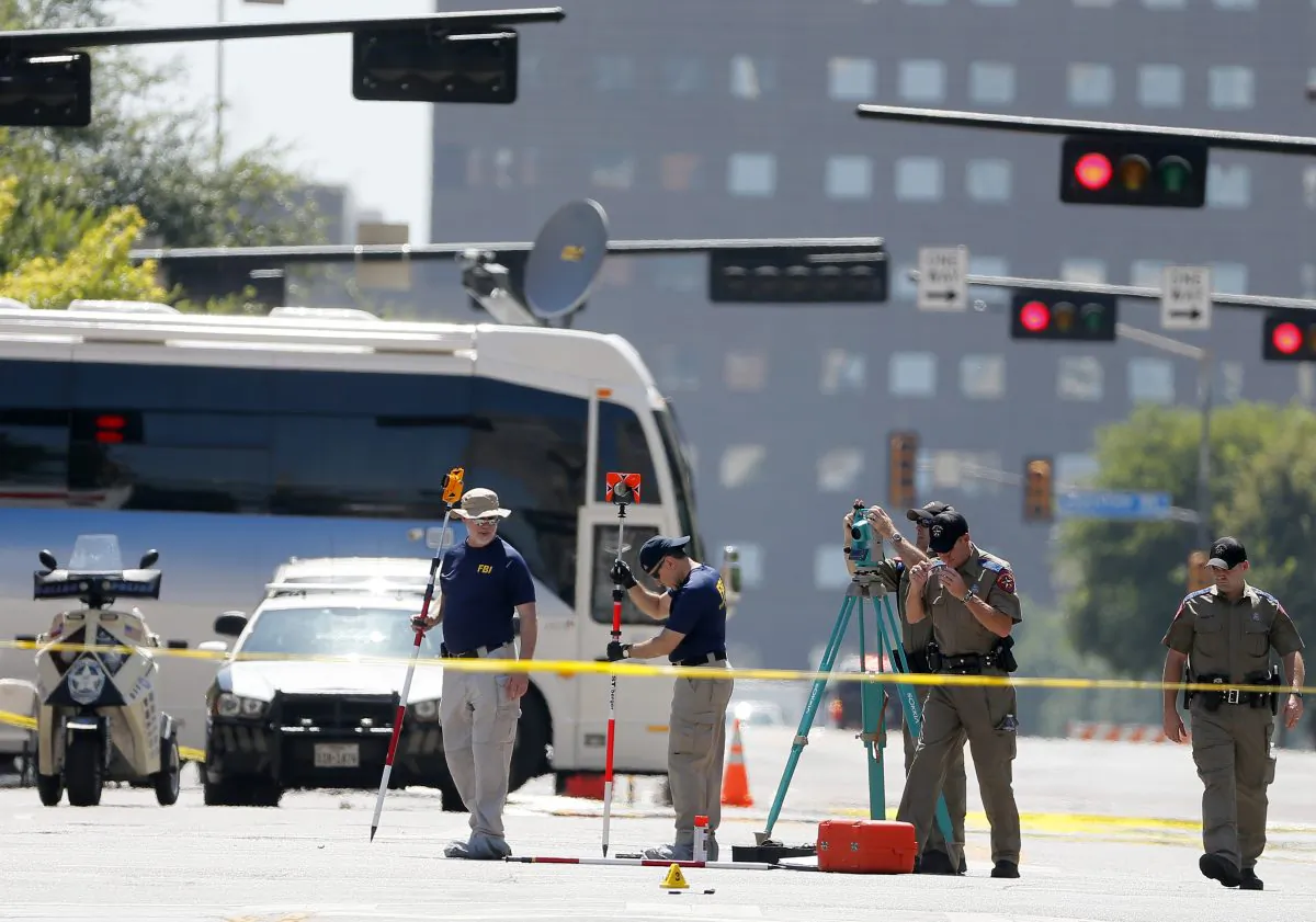 FBI agents and other law enforcement officers investigate the scene of a Thursday night shooting that left five police officers dead in Dallas on July 8, 2016. (AP Photo/Tony Gutierrez)