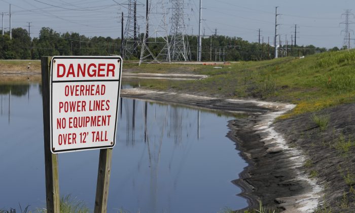 A danger sign warns of power lines near a Coal ash pond from an abandoned coal fired power plant are close to the Elizabeth River in Chesapeake, Va., Monday, June 27, 2016. A lawsuit has gone to a judge over environmentalists claim that there are leaks of arsenic and other heavy metals into a river near Dominion's abandoned Chesapeake power plant in violation of the Clean Water Act. (AP Photo/Steve Helber)