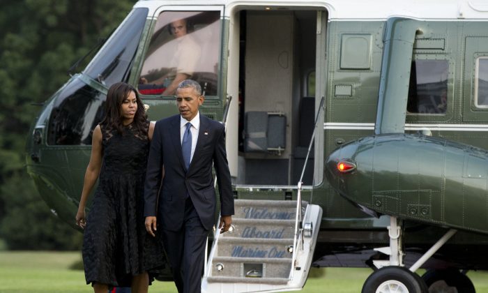 President Barack Obama and first lady Michelle Obama walk across the South Lawn of the White House from Marine One, Tuesday, July 12, 2016, in Washington, as they return from Dallas where they attended a memorial service for five fallen Dallas police officers. (AP Photo/Carolyn Kaster)